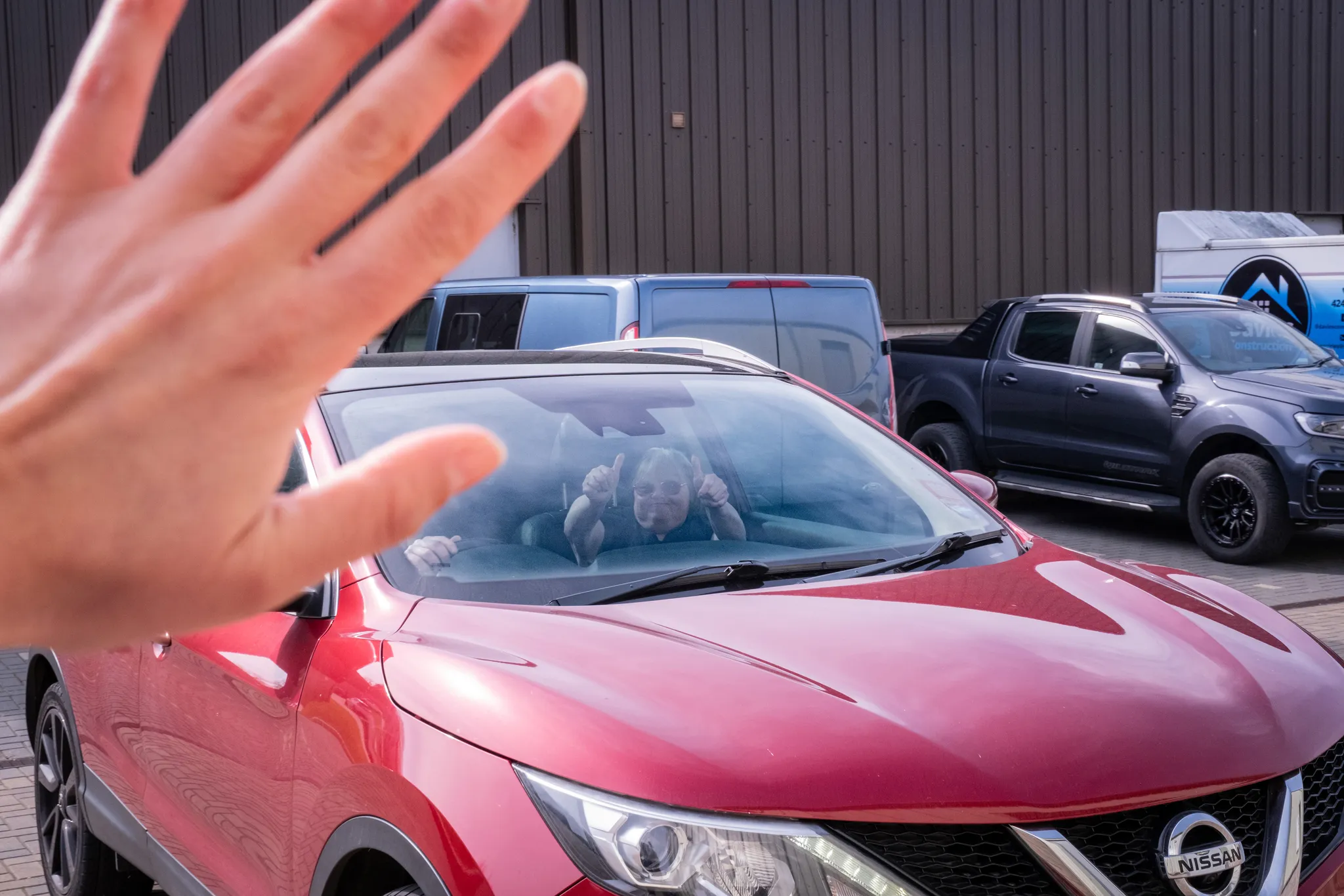 Julie Naylor waving from inside a car on arrival at MyGym on the Isle of Man during filming for the World Down Syndrome Day film by DotPerformance